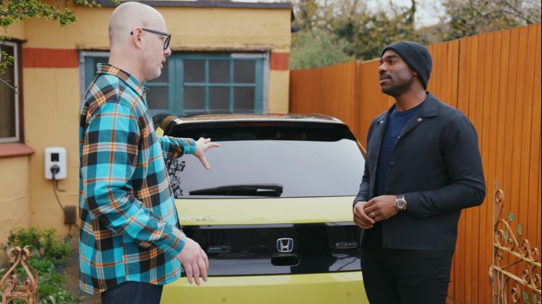 Ore Odube talking to a Honda e:PROGRESS customer in front of a yellow Honda vehicle